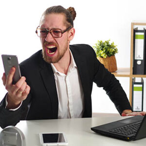 Man looking at computer and smart phone with enraged expression.